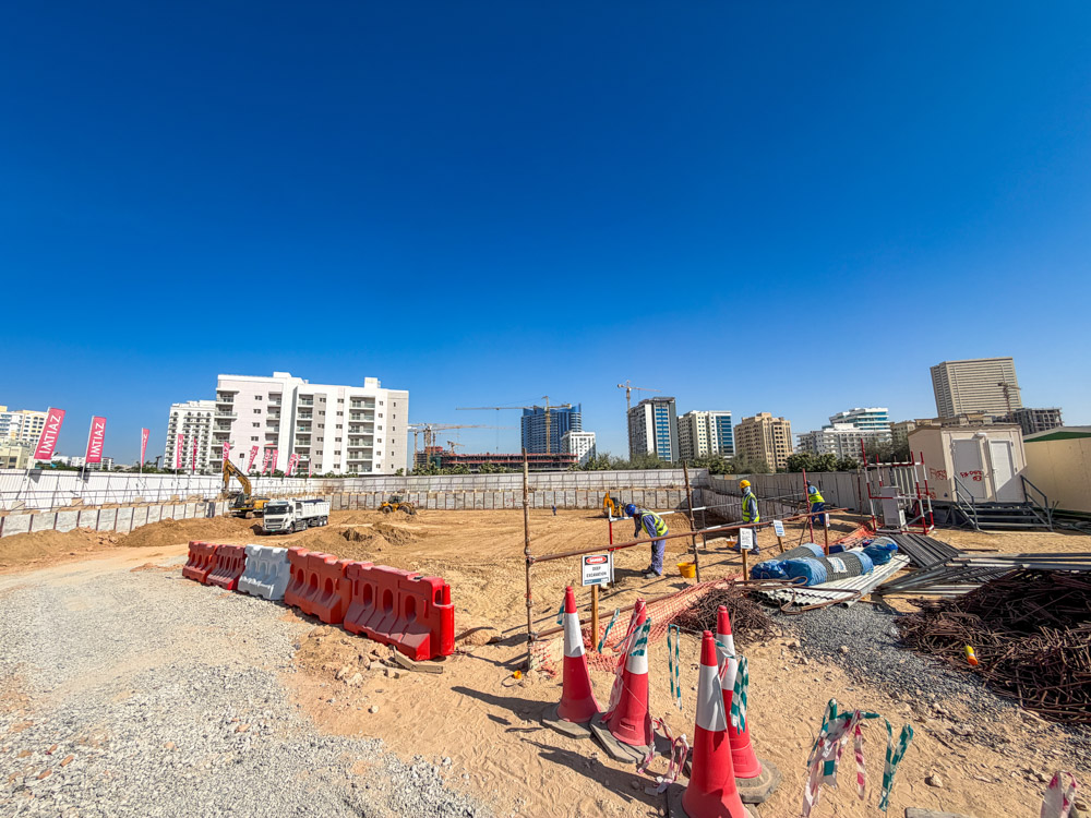 Cove Grand By Imtiaz Construction site with machinery, workers, safety cones, and buildings under a clear blue sky.
